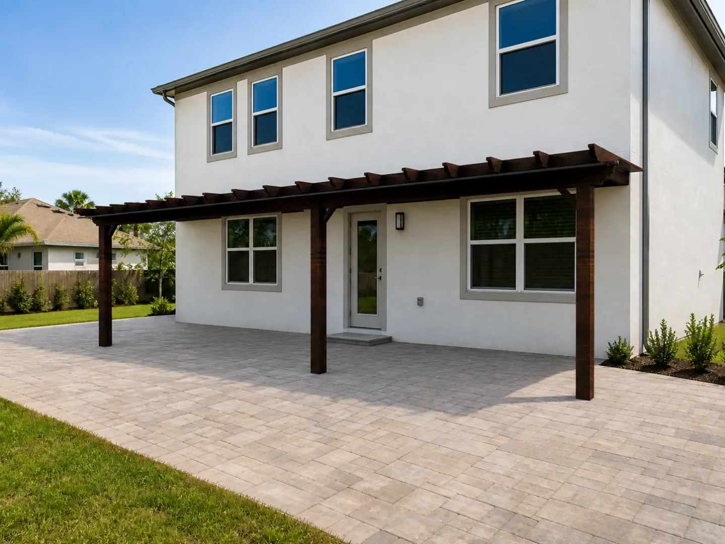 Visualisierung einer dunklen Holzpergola über der gepflasterten Terrasse eines weissen Hauses.